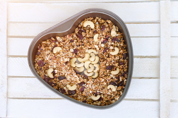 Granola on a  baking sheet heart shaped on a light white background.