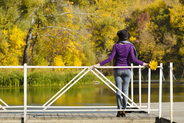 Girl in hat standing on the dock. Autumn, sunny.  Back view