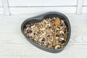 Granola on a  baking sheet heart shaped on a light white background.
