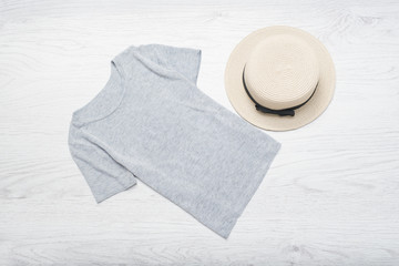 Fashionable concept. Female summer wardrobe. Straw hat and gray t-shirt. Top view