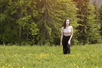 Young woman with a bouquet of flowers walking in a meadow.