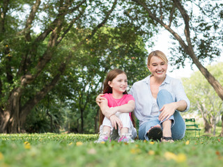 Naklejka na ściany i meble Mother and daughter playing together in the park. Happy family concept.
