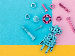 Metal robot, screws and washers colored with multicolored paint. Colorful background. Pink, blue,...