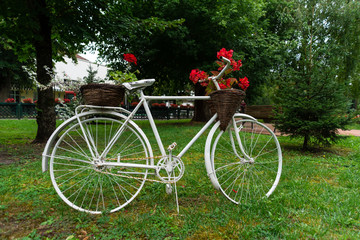 Fototapeta na wymiar white old bicycle with a basket of flowers as decoration in the park