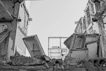 The remains of the destroyed building of a large industrial facility. Background. Black and white image
