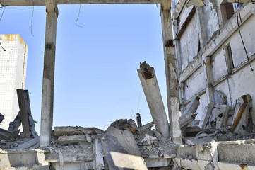 Remains of the destroyed industrial building. Large concrete piles with hanging on the rebar with...