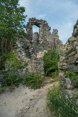 The ancient ruins of the old castle are overgrown with grass and shrubs with stones that have fallen out from time and weather from the walls.