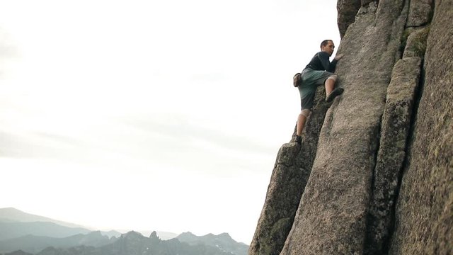 A selfless man climbs to the top of the cliff without a rope.