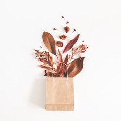 Autumn composition. Paper bag with autumn dried flowers and leaves on whute background. Flat lay,...