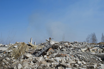 The rebar sticking up from piles of brick rubble, stone and concrete construction debris on the background of smoke
