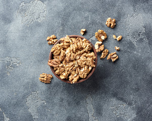 Walnut kernels on gray background with copy space. Nuts in clay bowl. Top view.