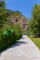a path in the park among green plants leading to a stony slope standing in the distance
