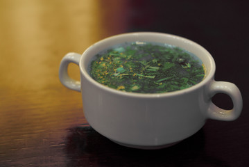 soup with fresh herbs on top in a plate on the table.