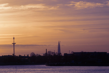 sunset with a river and a high-rise building in the distance.