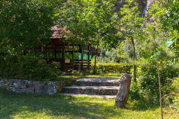 Stone steps leading to a wooden gazebo with a red roof against a rocky mountain
