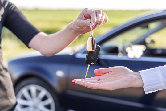 One woman hands over another car key. Rent or purchase of auto.