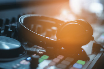 Hands of dj tweak various track controls on dj's deck,selective focus, close up. Dj Music concept.Black headphones for professional disc jockey.