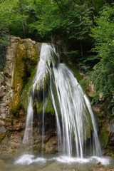 Fototapeta na wymiar Beautiful scenic big waterfall against the backdrop of stone rock and green plantations