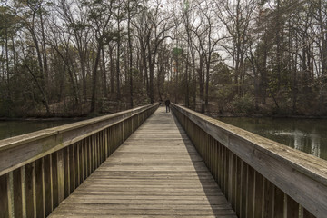 Fototapeta na wymiar Man crossing on a wooden bridge over a river