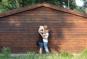 young happy family hugging together kissing son