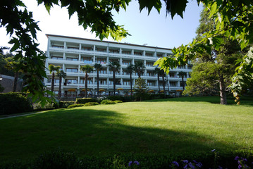 Obraz premium A modern building of a sanatorium complex in the shadow of tall palms and exotic plants