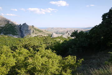 View from the top to the nearby rocky mountains and the endless blue sea in the distance