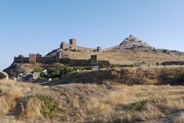 Ruins of stone wall fences with towers for patrols on hills with dry grass