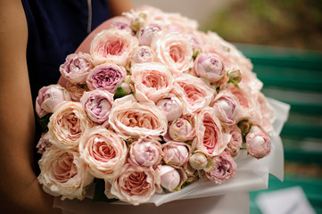 Girl holding a beautiful bouquet of pastel color rose peonies