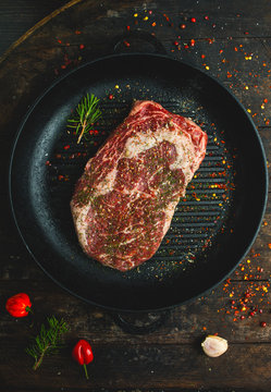 Raw fresh ribeye steak with seasonings and rosemary