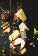 Assorted cheeses with grapes, nuts and rosemary