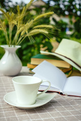 cup with tea, a laptop, a computer, a bookshine table in the garden on a summer morning, a place to work, a concept of freelancing