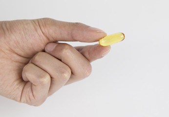 Vitamin And Supplement. Closeup Of Taking Yellow Fish Oil Pill. Hand Putting Omega-3 Capsule. Healthy Eating And Diet Nutrition Concepts. High Resolution Image.