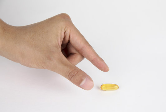 Vitamin And Supplement. Closeup Of Taking Yellow Fish Oil Pill. Hand Putting Omega-3 Capsule. Healthy Eating And Diet Nutrition Concepts. High Resolution Image.