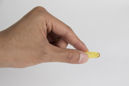 Vitamin And Supplement. Closeup Of Taking Yellow Fish Oil Pill. Hand Putting Omega-3 Capsule. Healthy Eating And Diet Nutrition Concepts. High Resolution Image.