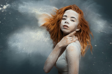 Dancing in flour concept. Cute fitness beauty redhead woman / female / adult dancer performer in dust / fog. Portrait of a girl dancer with ginger hair in flour on isolated backround
