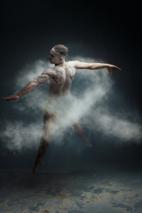 Dancing in flour concept. Muscle fitness guy man male dancer in light blue dust / fog. Guy making dance element in flour cloud. White ribbon as a symbol of lung cancer concept.