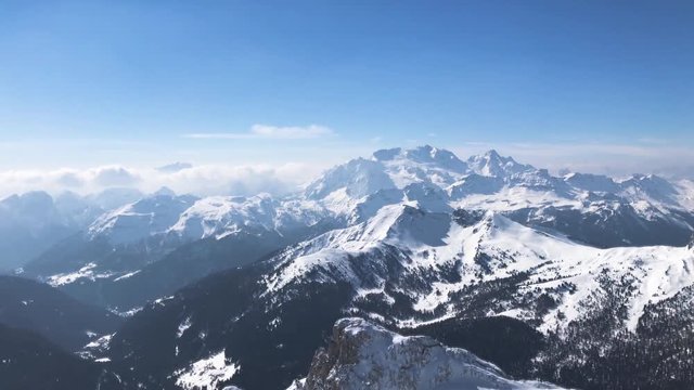 Beautiful panoramic view on snowy mountains with birds flying over a rock in winter Alps in Italy