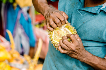 A man is cutting a durian.
