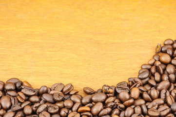 Coffee beans on brown wood background with copy space.