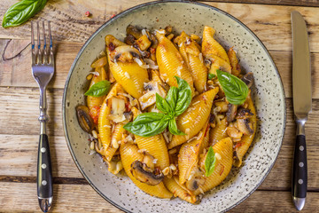 Pasta Conchiglioni with mushrooms in a vintage bowl on concrete background.