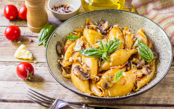 Pasta Conchiglioni with mushrooms in a vintage bowl on concrete background.