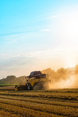 big combine harvester threshing in the sunset.