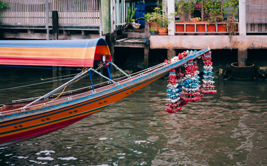 Fototapeta na wymiar Bow of Thai long tail boat with garlands in Banhkok canal (Klong), famous river transportation