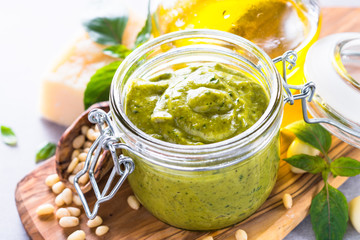 Pesto sauce in glass jar and ingredients. 