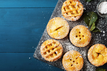 Delicious mini apple pies on blue background from above. Autumn pastry desserts.