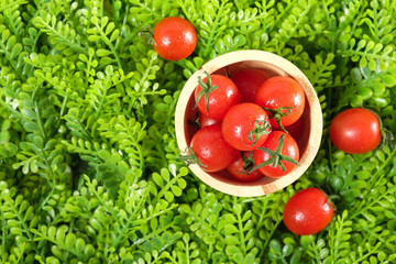 Ripe cherries tomatoes or mini tomatoes in a wooden bowl.