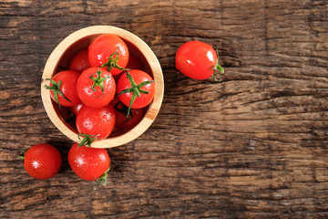 Ripe cherries tomatoes or mini tomatoes in a wooden bowl.