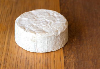 Camembert cheese round on oak wooden board close up