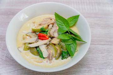 the white bowl of Green Curry with chicken, Thai delicious food on wooden table background.