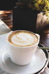 Cappuccino cup on coffee table near plant, Image made in the Bratislava castle Cafe, Slovakia